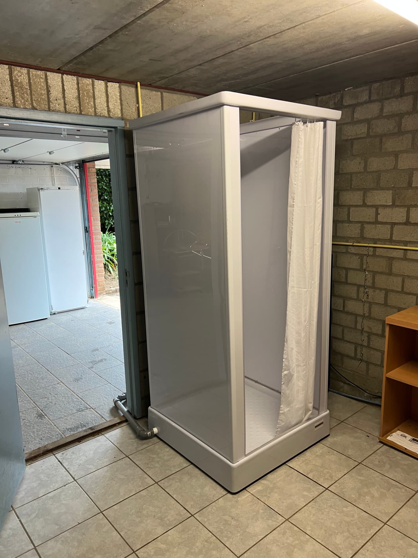 De tijdelijke douchevoorziening geplaatst in de wasruimte naast de inpandige garage