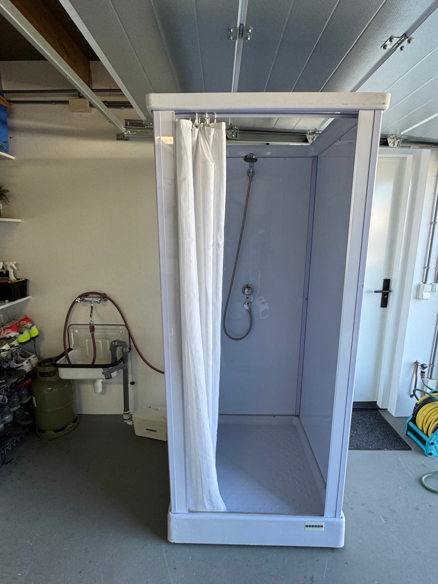 Mobiele douchecabine in een garage in Chevremont met vuilwaterpomp tijdens een badkamerverbouwing