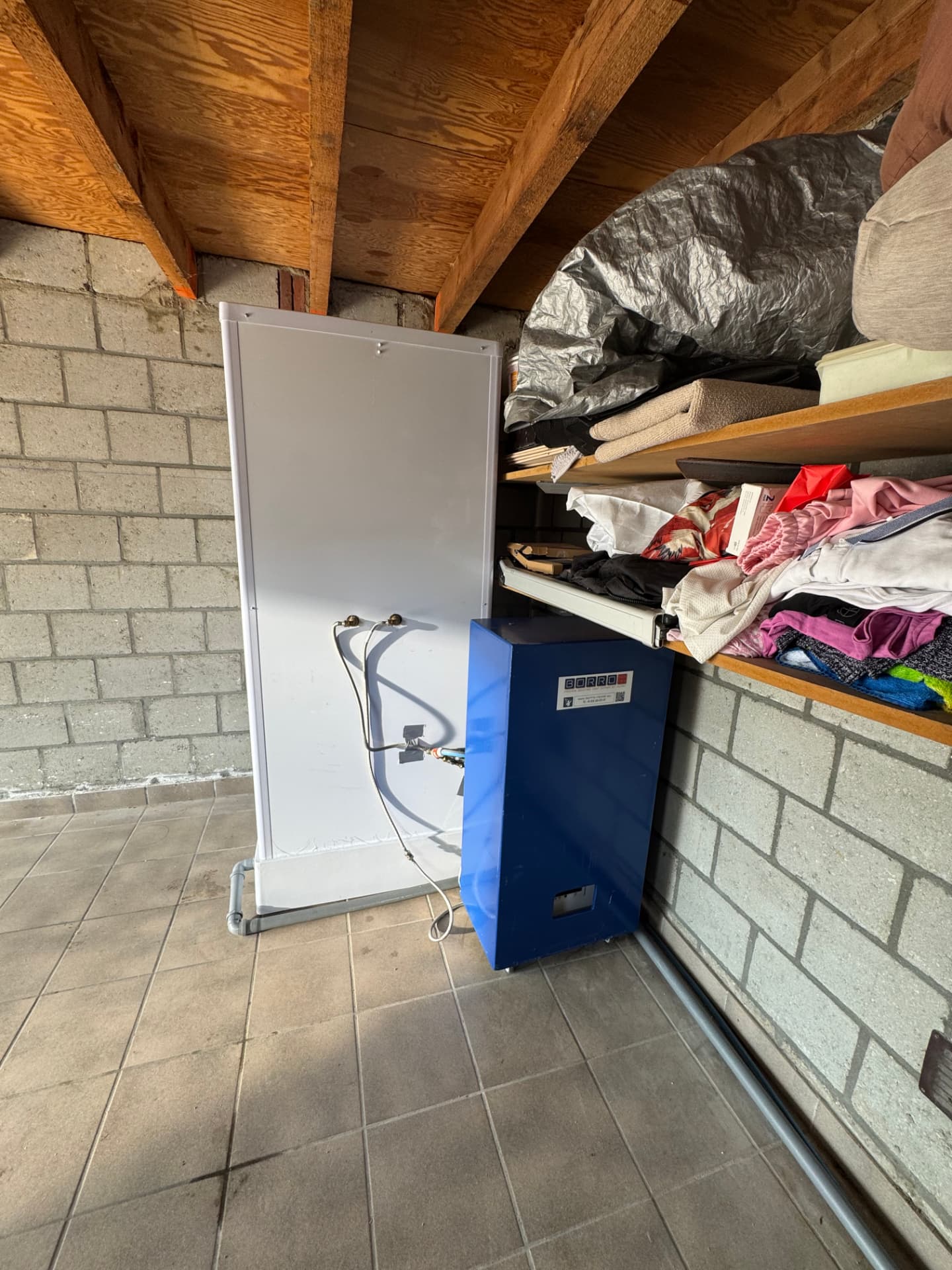 Achterzijde van de mobiele douchecabine met blauwe boiler in een garage in Chevremont