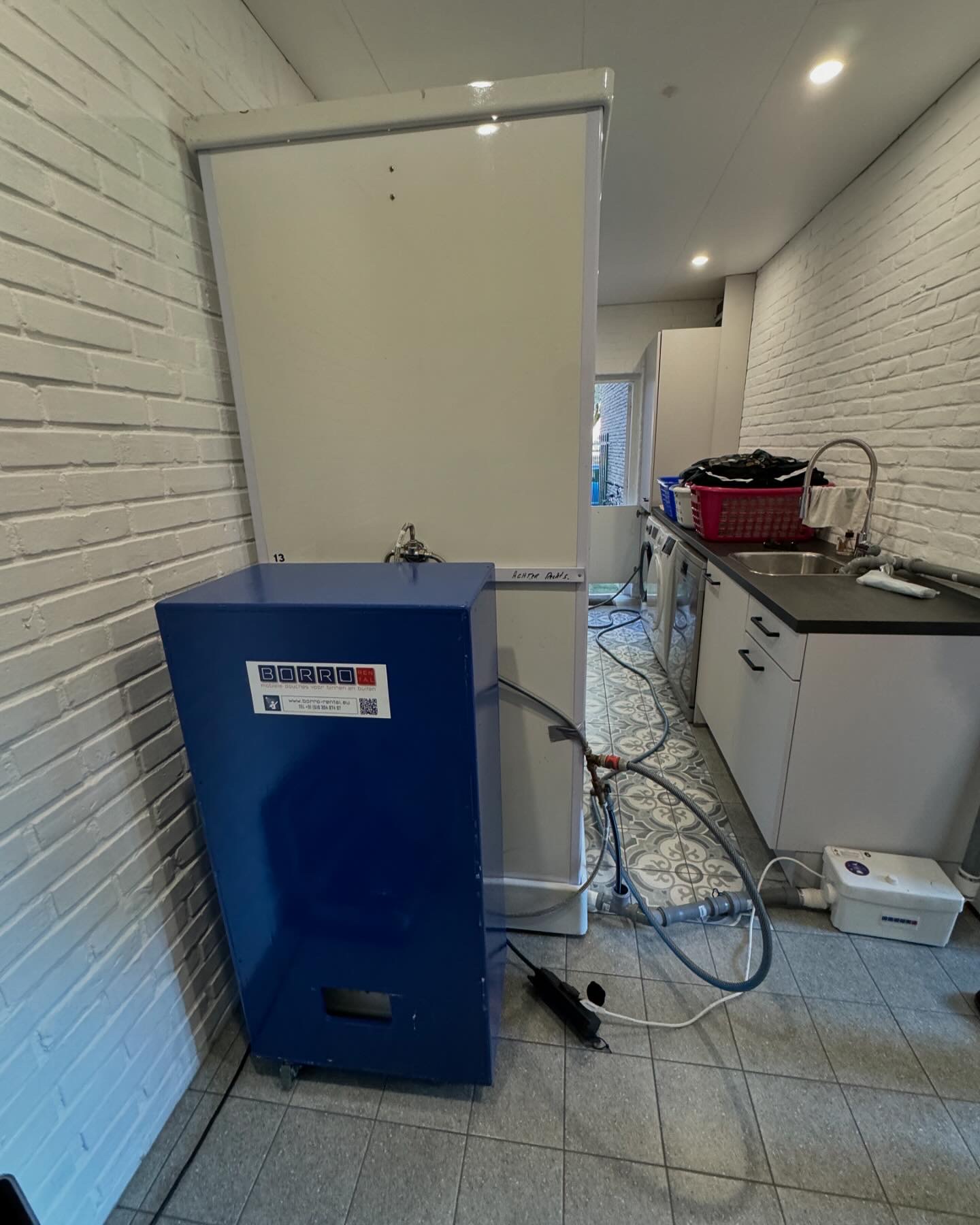 Mobiele douche met boiler en vuilwaterpomp in een bijkeuken/wasruimte in Geleen