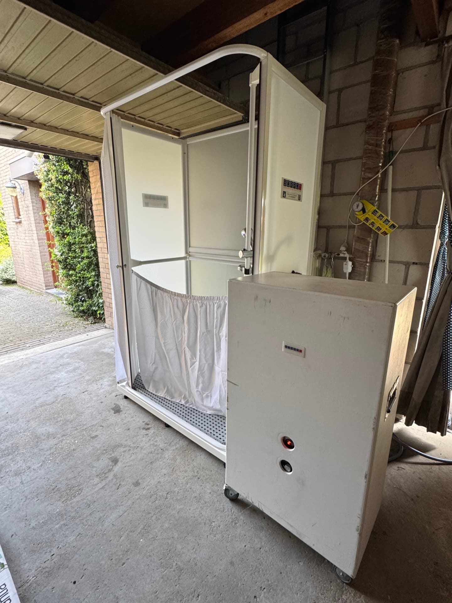 Mobiele zorgdouche geplaatst in een garage, met een mobiele 80-liter boiler voor de warmwatervoorziening.