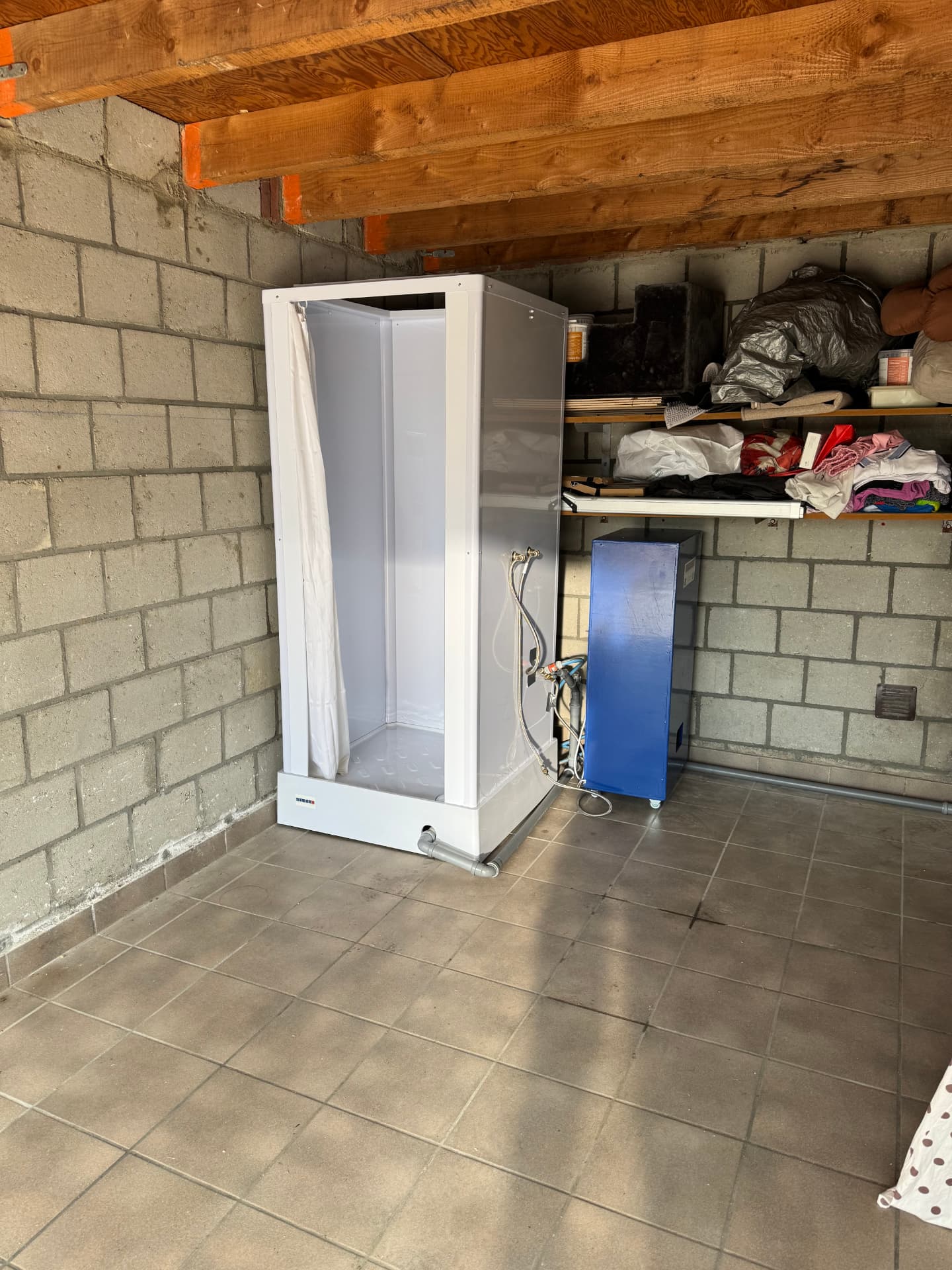 Mobiele douchecabine met blauwe mobiele boiler in een garage in Chevremont na een brand