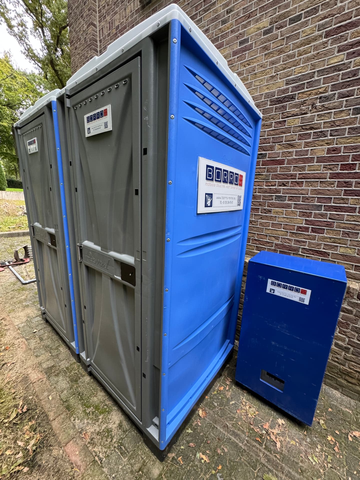 Twee mobiele buitendouchecabines van Borro-Rental met een blauwe mobiele boiler op locatie
