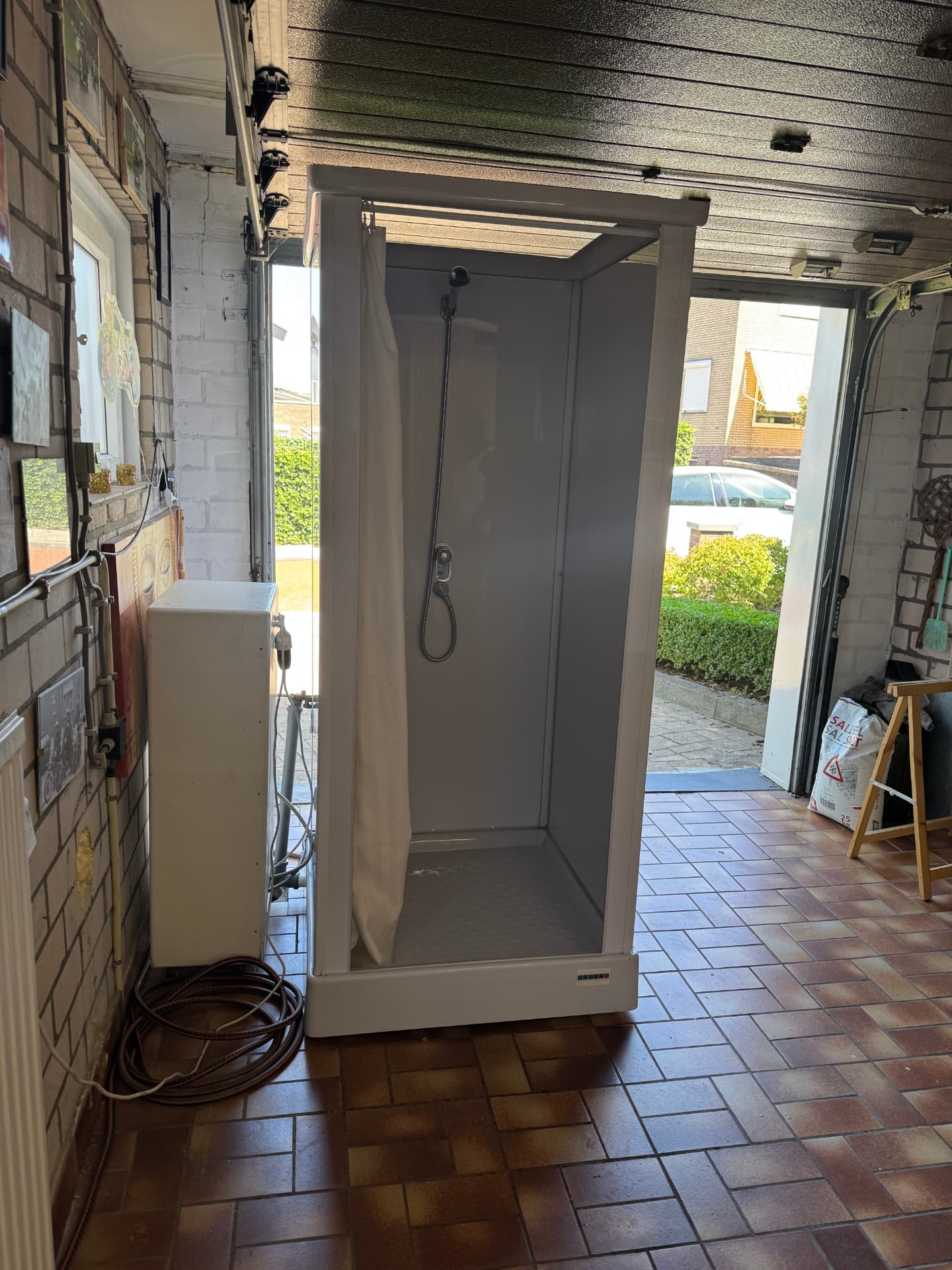 Mobiele douchecabine met gordijn en boiler in een garage in Brunssum
