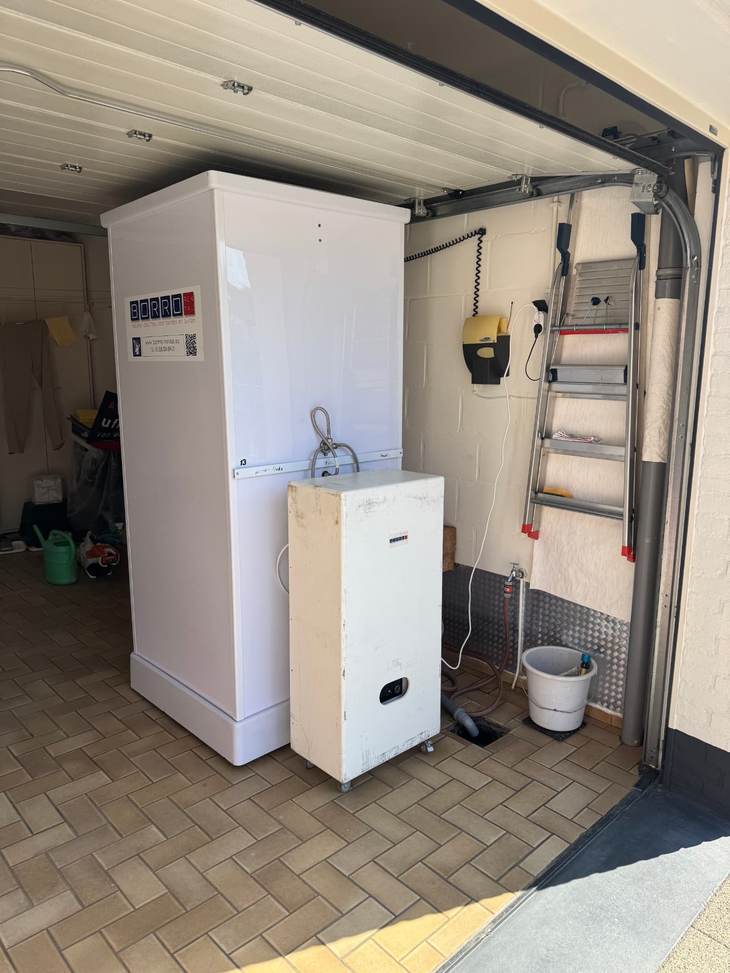 Mobiele douche met mobiele boiler opgesteld in een garage tijdens een badkamerverbouwing